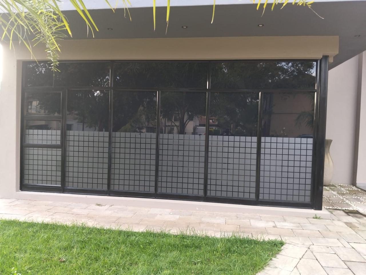 Residential window with custom grid frosting privacy film on lower panel and dark solar film above